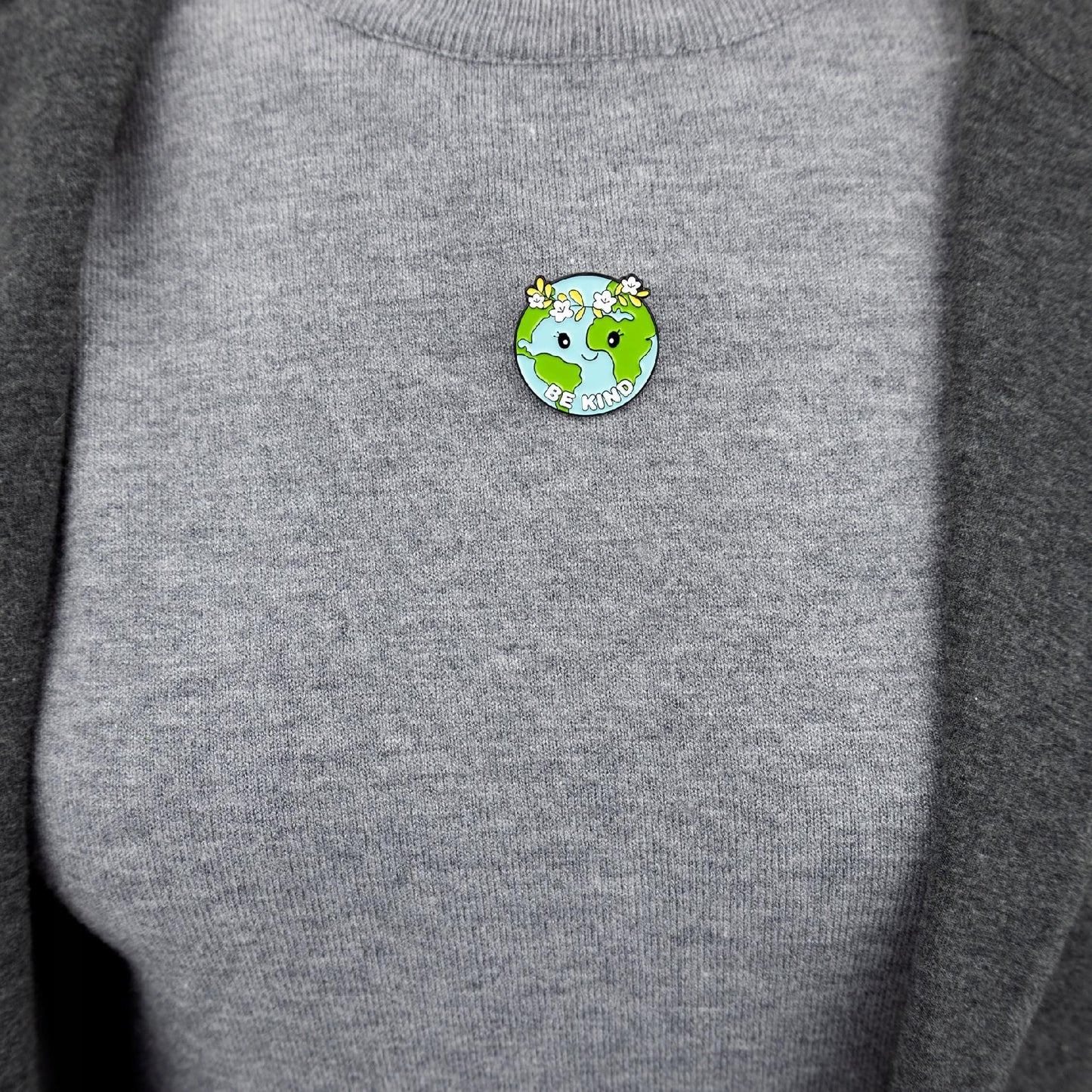 Insignă ecologică în formă de planetă Pământ cu o coroană cu sloganul „Fii bun”