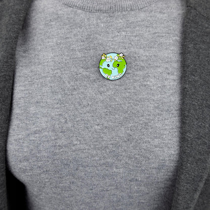 Insignă ecologică în formă de planetă Pământ cu o coroană cu sloganul „Fii bun”